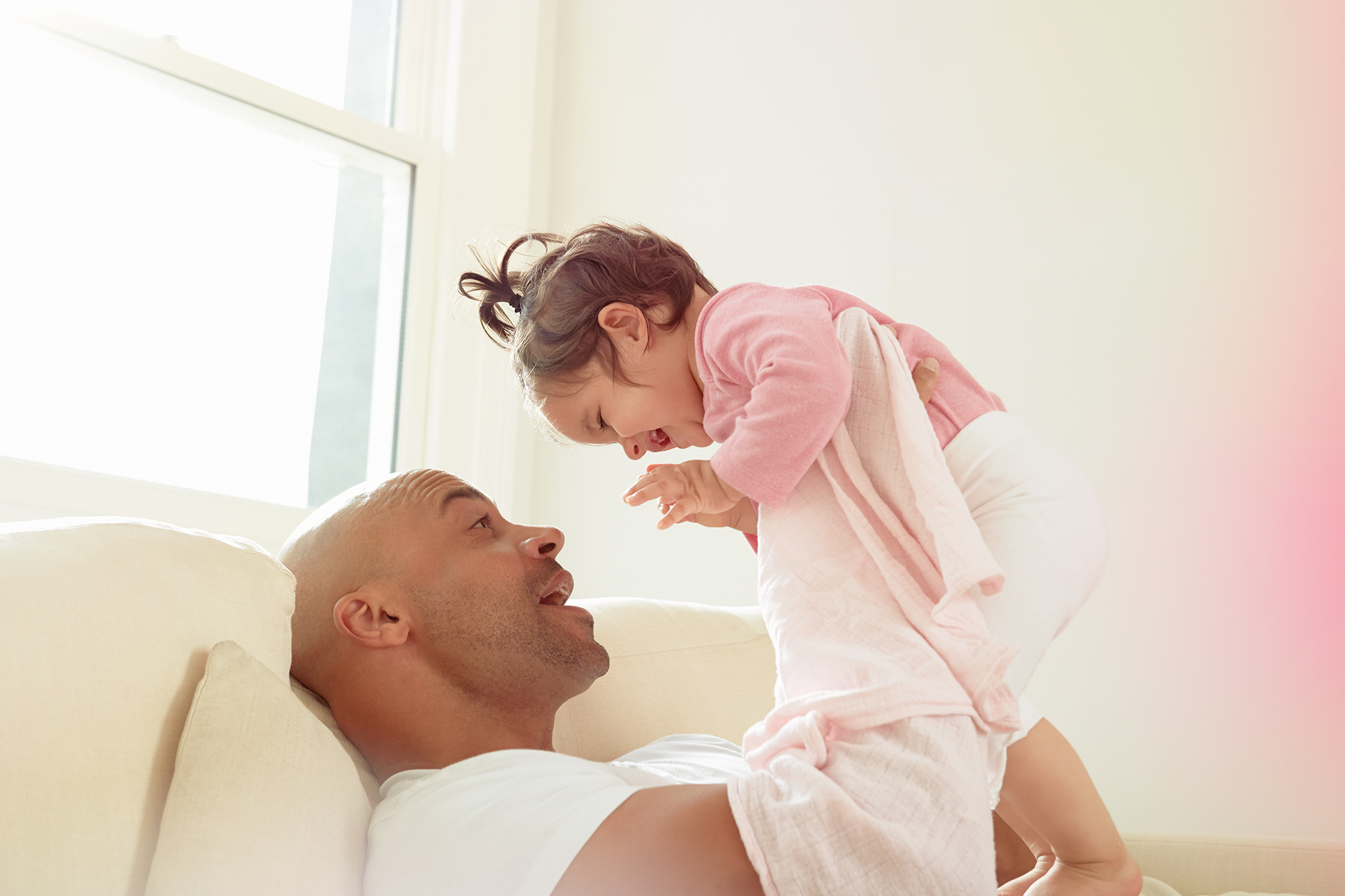 Father lifting baby girl above head at home