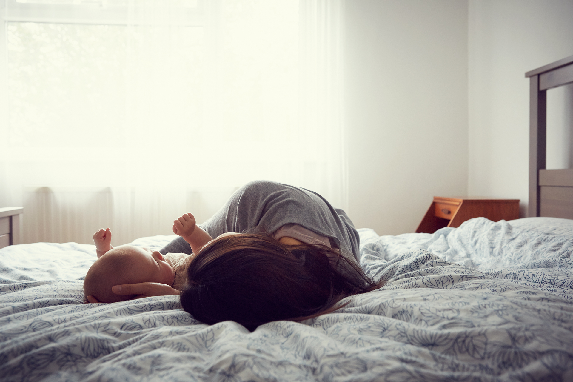 Mother and baby laying on bed in early morning