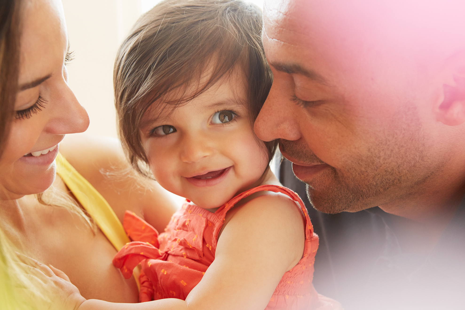 Family embrace with smiling baby in morning light
